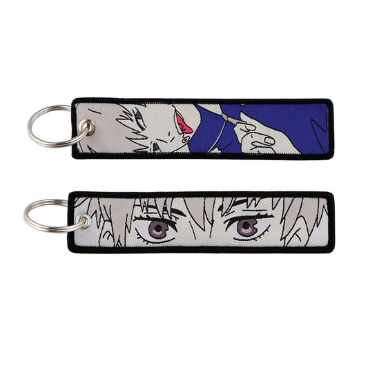 Porte-clés Jujutsu Kaisen Toge Inumaki Bleu Marine : en tissu bleu marine, deux lanières rectangulaires avec visages manga.