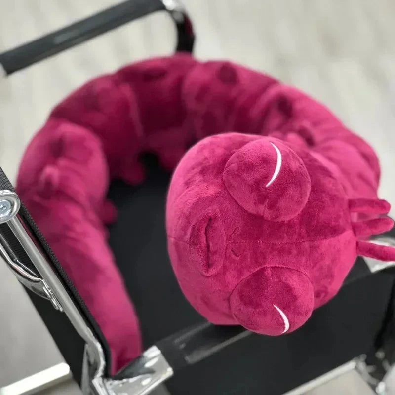 Peluche violette, tête duveteuse et longue patte en plusieurs sections, détails brodés.